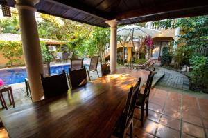 een houten tafel en stoelen op een patio met een zwembad bij Anona Guesthouse in Playa Hermosa