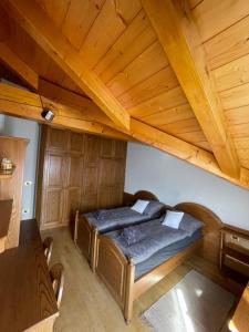 Ce lit se trouve dans un dortoir doté d'un plafond en bois. dans l'établissement Apartman Anda, à Cavalese