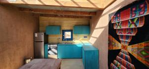 聖佩德羅·德·阿塔卡馬的住宿－Qhapaq Ñam Catarpe，厨房配有蓝色橱柜和冰箱。