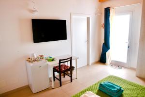 een woonkamer met een tafel en een tv aan de muur bij Una Vita In Vacanza in Comiso