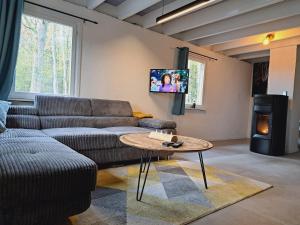 een woonkamer met een bank, een tafel en een tv bij Le refuge du KL in Bomal