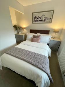 a bedroom with a large white bed with two lamps at Compact Modern Apartment Single Person or Couple Only in Bangor