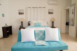 a bedroom with two beds and a blue couch at Villa Serenity by the Water in Providenciales