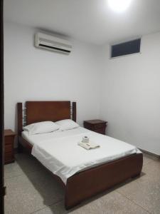 um quarto com uma cama com lençóis brancos e uma vela. em Hotel Los Arcángeles em Cúcuta