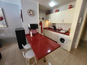 een keuken met een rode tafel en een magnetron bij Olivia Sunset 2 in Puerto de Santiago