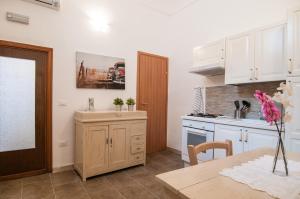 een keuken met witte kasten en een houten tafel bij Casa vacanze Cristina in Noto