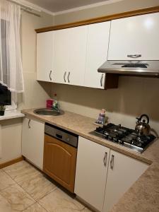 a kitchen with white cabinets and a stove and a sink at Mieszkaj U Marty in Jaworzno +17 photos