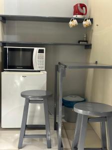 a small kitchen with two stools and a microwave at Nascer Do Sol Suites in Guarda do Embaú