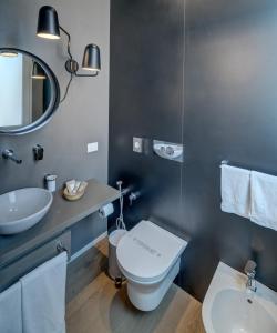 a bathroom with a toilet and a sink and a mirror at Le Palmette Suites in Cagliari