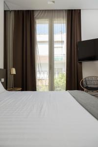 a bedroom with a large white bed and a window at Le Palmette Suites in Cagliari