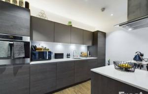 une cuisine avec des placards gris et un comptoir dans l'établissement Staines Home Stay, à Staines upon Thames