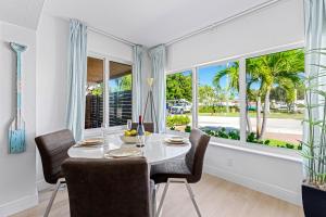 a dining room with a table and chairs and windows at Wonderful 3br Steps To The Beach Wheated Pool in Fort Lauderdale