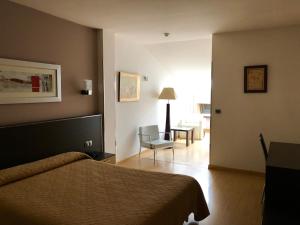 um quarto com uma cama e uma cadeira num quarto em Hotel Villa de Cacabelos em Cacabelos