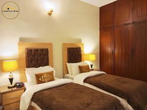 una camera d'albergo con due letti e due lampade di Grand Peace House I a Islamabad