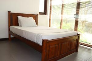 a bed with a wooden frame in a room with a window at Gampaha Heritage in Gampaha