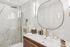 ein weißes Badezimmer mit einem Waschbecken und einem Spiegel in der Unterkunft Suite luxueuse avec jardin privé Sauna et Jacuzzi in Paris