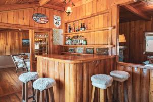 eine Bar in einem Zimmer mit Holzwänden und -hockern in der Unterkunft Hostería Villarino in San Martín de los Andes