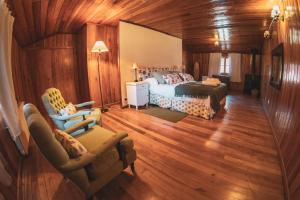 a bedroom with a bed and a couch and a chair at Hostería Villarino in San Martín de los Andes