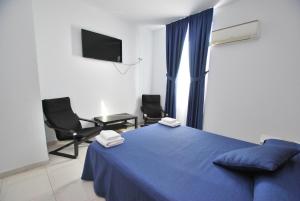a bedroom with a blue bed and two chairs at Hotel Tres Leones in Vilassar de Mar