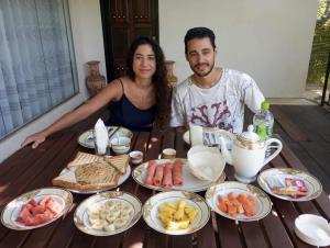 Um homem e uma mulher sentados à mesa com comida. em Village Mango Resort Yala em Tissamaharama