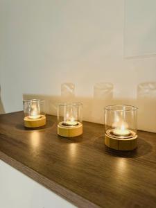 three candles are sitting on a wooden table at studio de charme in Perpignan