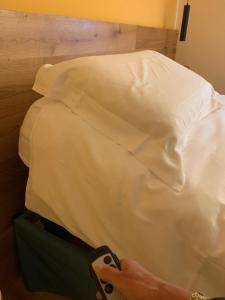 a person is standing next to a white bed at Agriturismo coda di gatto in Eraclea