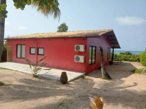 a red house with a palm tree in front of it at A janela do amanhecer in Maxaranguape
