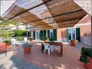 une terrasse avec une pergola en bois, une table et des chaises dans l'établissement Quinto Canto Moneglia, à Moneglia