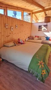 Cama grande en habitación con paredes de madera en ArboLodge, en Vichuquén