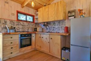 cocina con armarios de madera y nevera blanca en ArboLodge, en Vichuquén