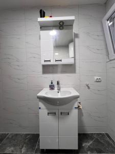 a white bathroom with a sink and a mirror at Apartmani River Priboj in Čitluk