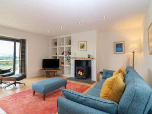 a living room with a blue couch and a fireplace at Whitehouse Woodwrae in Forfar