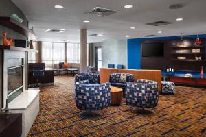 a lobby with chairs and a couch and a television at Courtyard by Marriott Portland Airport in South Portland