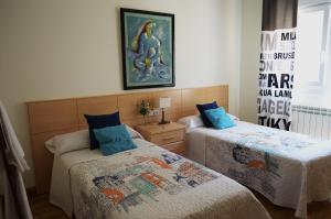 1 dormitorio con 2 camas y un cuadro en la pared en Pensión Ostadar, en Los Arcos