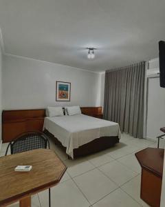 ヴァールゼア・グランデにあるMarion Pantanal Hotelのベッドとテーブルが備わるホテルルームです。