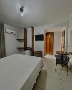 a bedroom with a large white bed and a table at Marion Pantanal Hotel in Várzea Grande