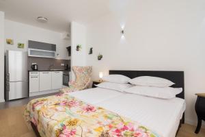 a bedroom with a large white bed with a kitchen at Bepo Studio Apartment - FREE PARKING in Split