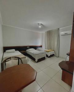 a hotel room with two beds and a table at Marion Pantanal Hotel in Várzea Grande