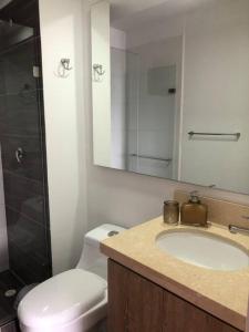 a bathroom with a sink and a toilet and a mirror at Apartamento amoblado- Marawi 806 in Armenia