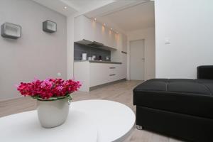 Modern Apartments في ماكارسكا: غرفة معيشة مع طاولة بيضاء وورود وردية