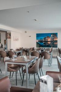a restaurant with tables and chairs and a painting on the wall at Brit Hotel Confort Saint-Lô in Saint Lo