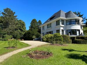 une grande maison blanche avec un toit gris dans l'établissement B&B Des Heures Claires, à Lasne