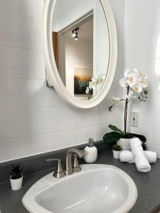 La salle de bains est pourvue d'un lavabo, d'un miroir et de serviettes blanches. dans l'établissement 18-26-30 Saint-Joseph Est, à Québec
