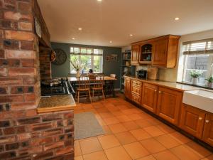 a kitchen with wooden cabinets and a brick wall at Pen Y Groes in Welshpool