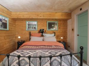 1 dormitorio con 1 cama en una habitación con paredes de madera en Brandeers Long Barn, en Malmesbury