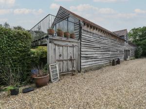 an old wooden building with a balcony and potted plants at Brandeers Long Barn in Malmesbury
