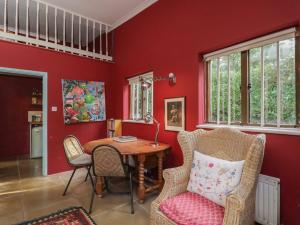 a living room with red walls and a table and chairs at Brandeers Studio in Malmesbury