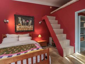 a bedroom with a red wall with a bed and a staircase at Brandeers Studio in Malmesbury