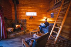 a man sitting on a couch in a log cabin with a fireplace at Baker Creek By Basecamp in Lake Louise