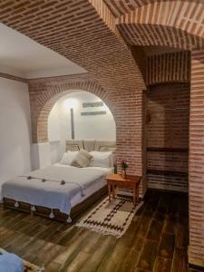 sypialnia z dużym łóżkiem i ceglaną ścianą w obiekcie Riad O LY w Marakeszu